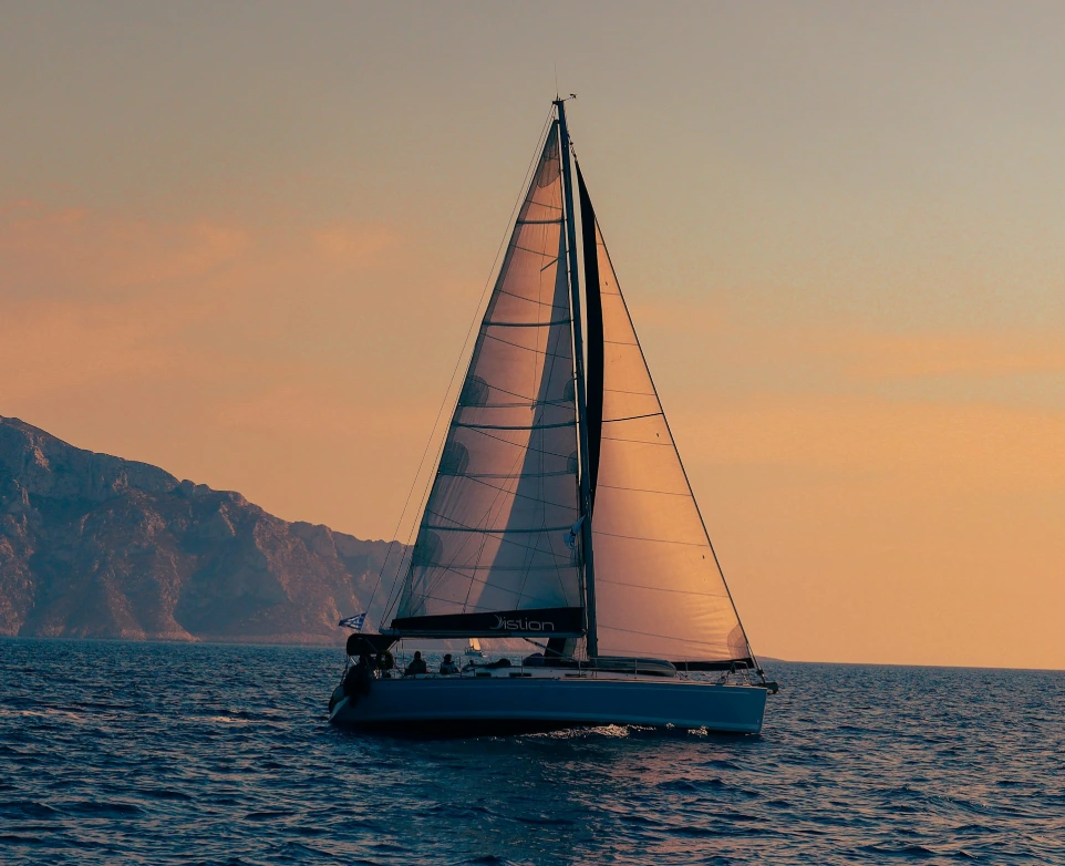 A sailboat sailing in the ocean at sunset